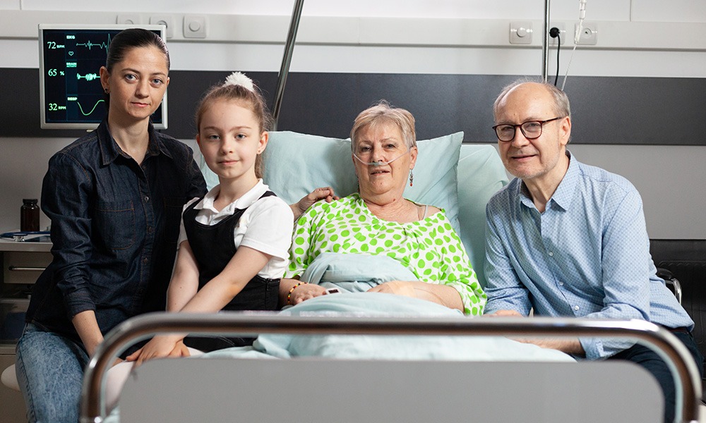 Portait of a patient on a hospital bed with family.