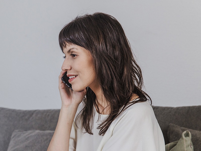 Woman speaking on phone, sitting on her couch