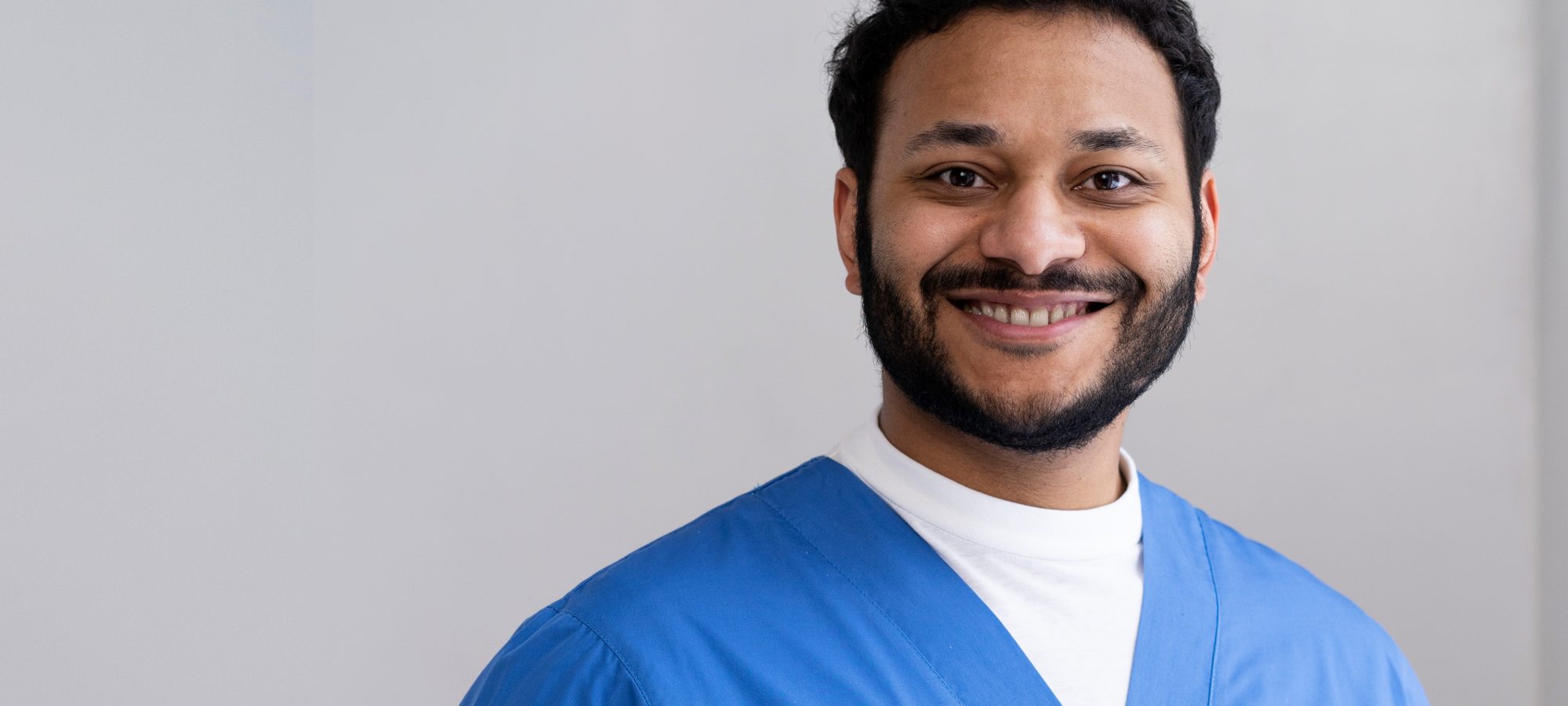 Healthcareworker in scrubs smiling at camera